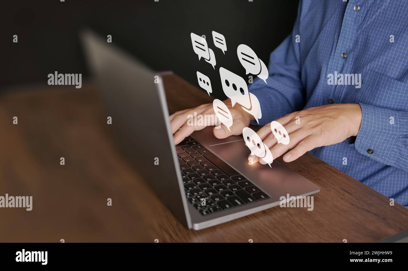 Chatta e rimani connesso tramite Internet. Un uomo usa un computer portatile per le comunicazioni online. Bollicine vocali virtuali o icone a fumetti durante l'utilizzo dei social network Foto Stock