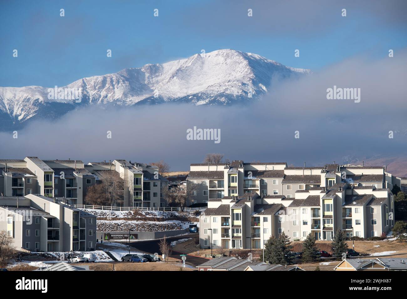 Una tempesta invernale sgorga sul Pikes Peak a Colorado Springs. Appartamenti, case a schiera e condomini ai piedi offrono splendide viste sulle montagne. Foto Stock