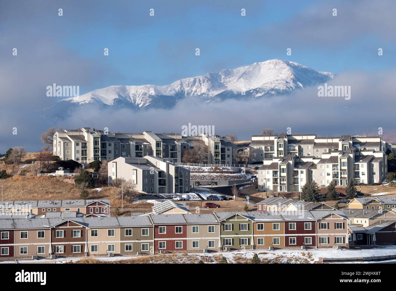 Una tempesta invernale sgorga sul Pikes Peak a Colorado Springs. Appartamenti, case a schiera e condomini ai piedi offrono splendide viste sulle montagne. Foto Stock