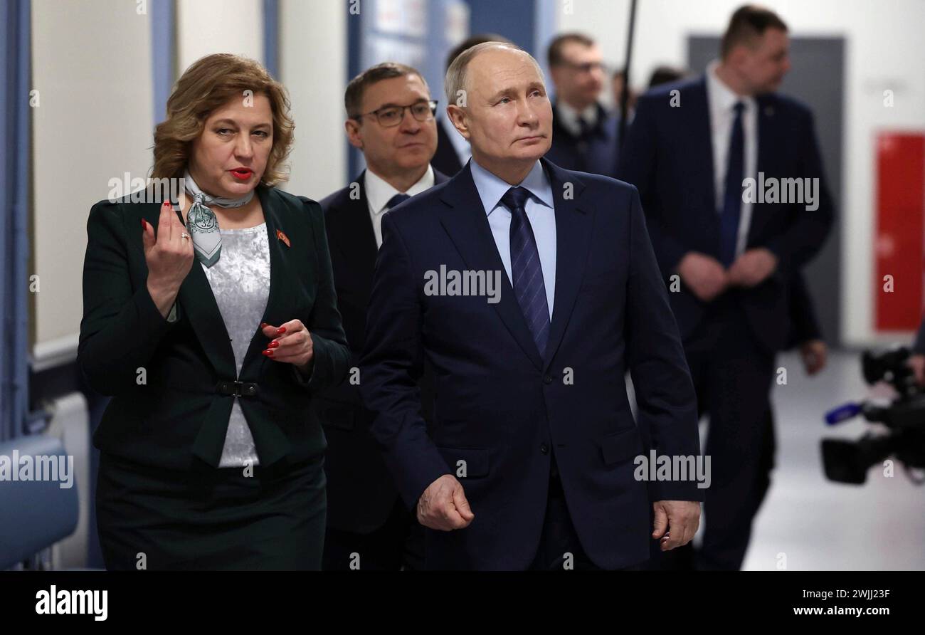 Nizhny Tagil, Russia. 15 febbraio 2024. Il presidente russo Vladimir Putin, a destra, accompagnato dal preside Galina Maslikova, a sinistra, e dall'inviato presidenziale degli Urali Vladimir Yakushev, al centro, visita una classe recentemente rinnovata alla scuola secondaria n. 32, 15 febbraio 2024 a Nizhny Tagil, Oblast di Sverdlovsk, Russia. Crediti: Alexander Kazakov/piscina del Cremlino/Alamy Live News Foto Stock