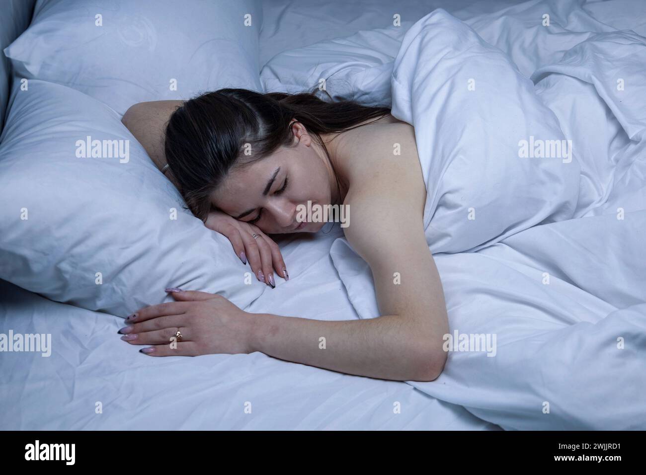 La ragazza dorme in un letto bianco. Foto Stock