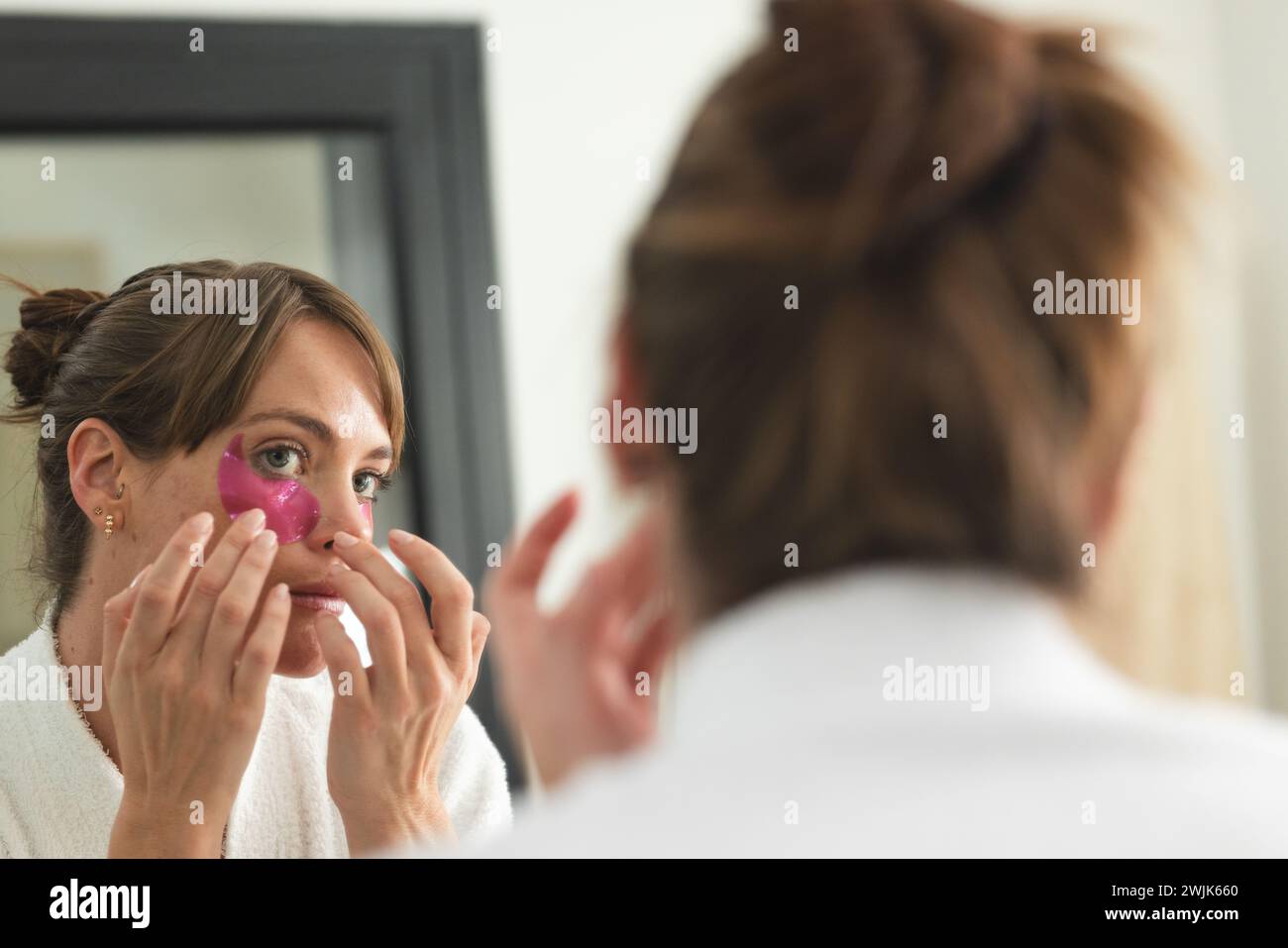 Donna caucasica applica una maschera per gli occhi rosa a casa Foto Stock