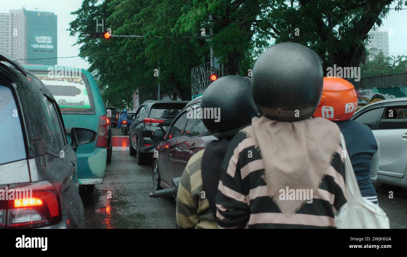 La città di Medan è animata da persone impegnate in varie attività, attraversando le sue strade in veicoli, intrecciando un vivace arazzo della vita urbana Foto Stock