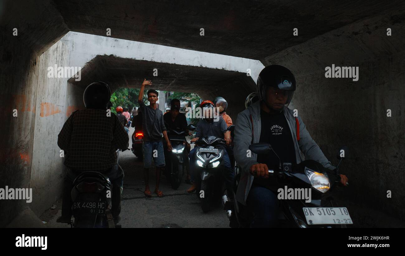 La città di Medan è animata da persone impegnate in varie attività, attraversando le sue strade in veicoli, intrecciando un vivace arazzo della vita urbana Foto Stock