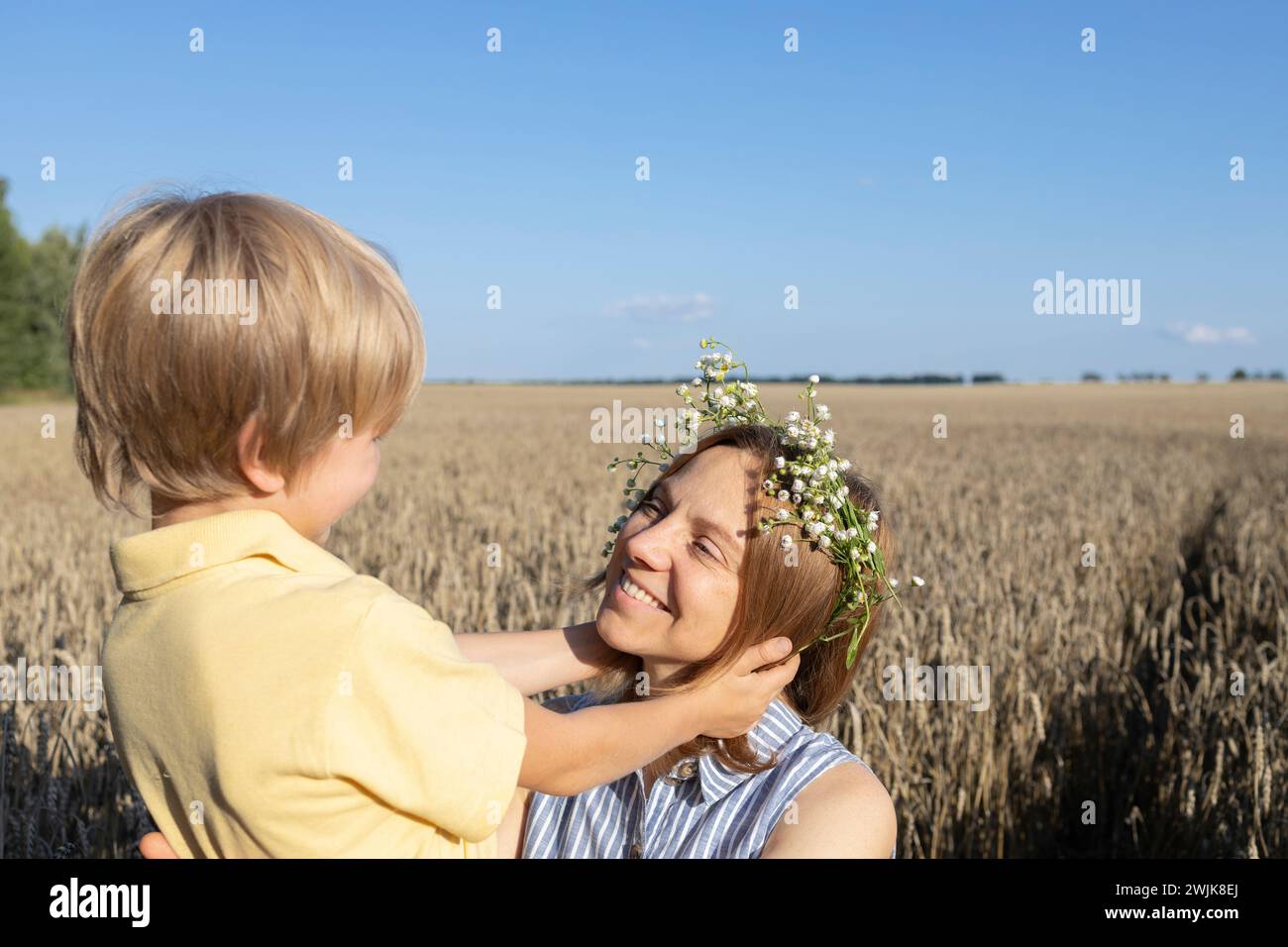 mamma e figlio felici in un campo di grano, il ragazzo tiene delicatamente la testa delle madri. concetto di amore parentale, maternità. Festa della mamma. goditi la natura e la vita, f Foto Stock