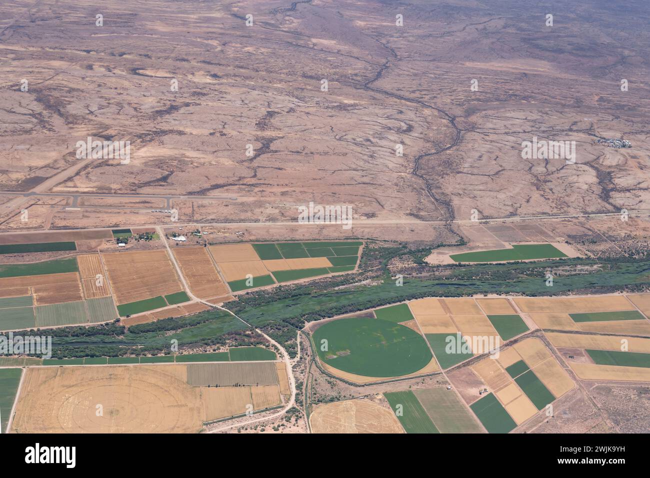 Paesaggio urbano aereo con campo d'aviazione e area agricola vicino al fiume Fish nel deserto, girato da un aereo aliante con la luce brillante della tarda primavera a Mariental, Na Foto Stock