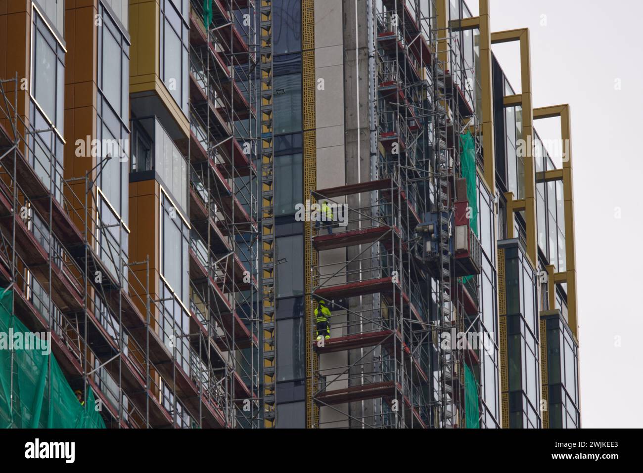 Operai edili in fase di ristrutturazione di un grattacielo e di costruzione su un ponteggio Foto Stock