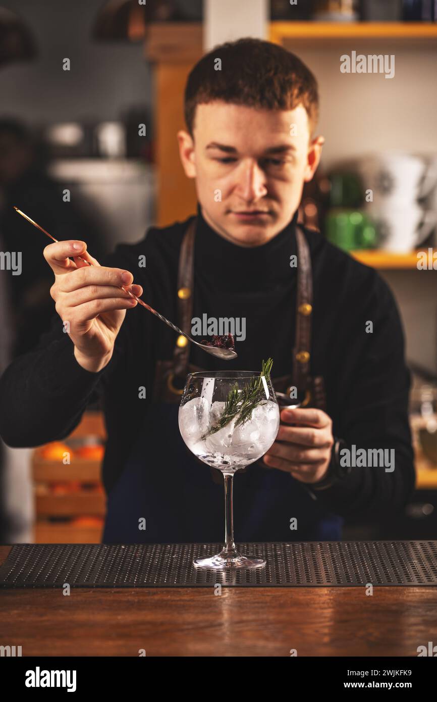 Il barista sta sta aggiungendo ingredienti in vetro al bancone del bar Foto Stock