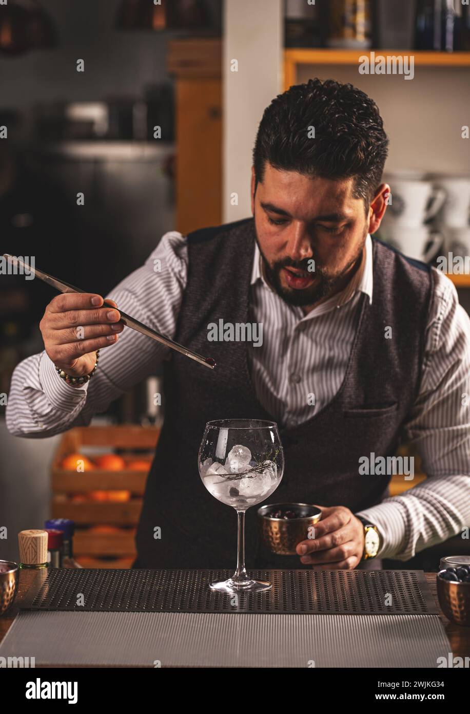 Il barista sta sta aggiungendo ingredienti in vetro al bancone del bar Foto Stock