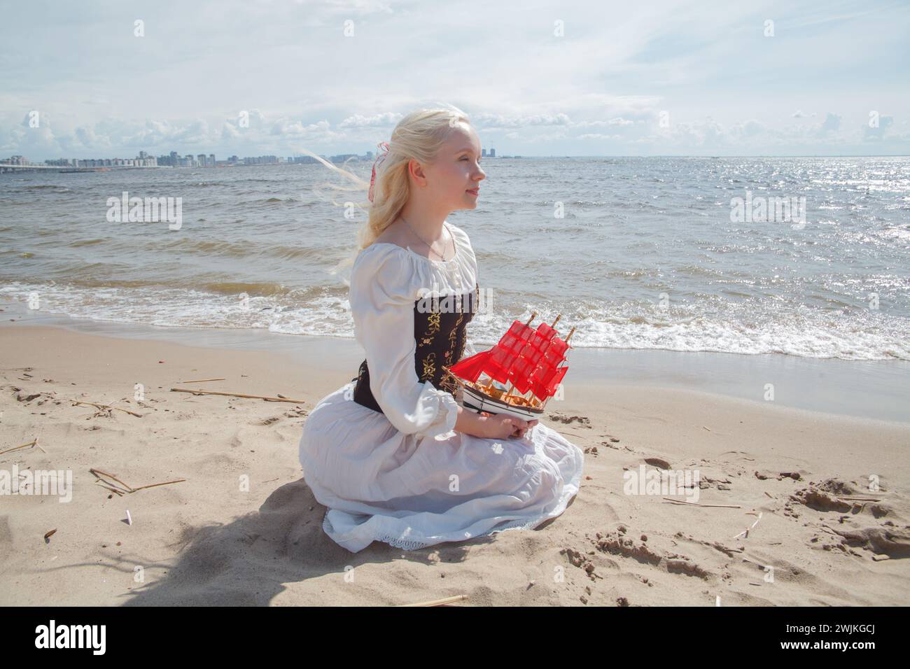 Romantico ritratto di bellezza di moda di una giovane donna adorabile che sogna e siede sulla spiaggia di mare all'aperto Foto Stock