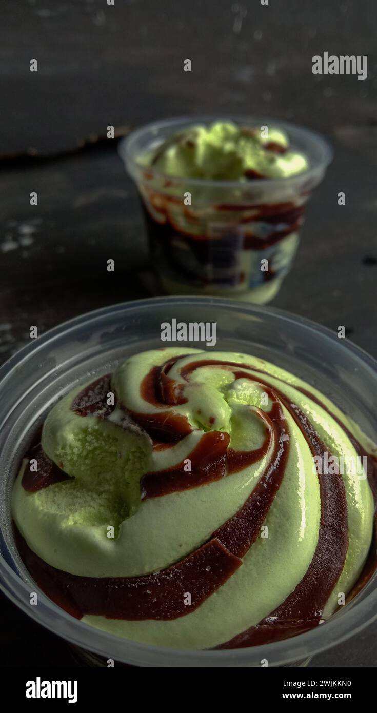 La foto è una foto di gelato al gusto di avocado in una tazza con sfondo nero Foto Stock