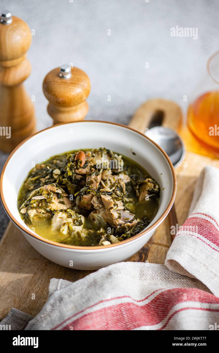 Piatto tradizionale georgiano Chakapuli nella ciotola servito sul tavolo con un bicchiere di vino ambrato Foto Stock