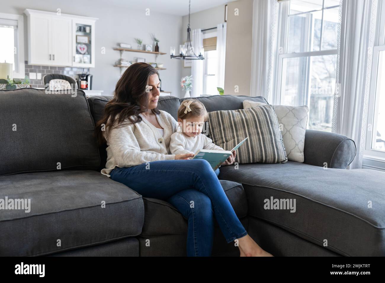 Madre e bambino seduti sul divano a leggere un libro Foto Stock