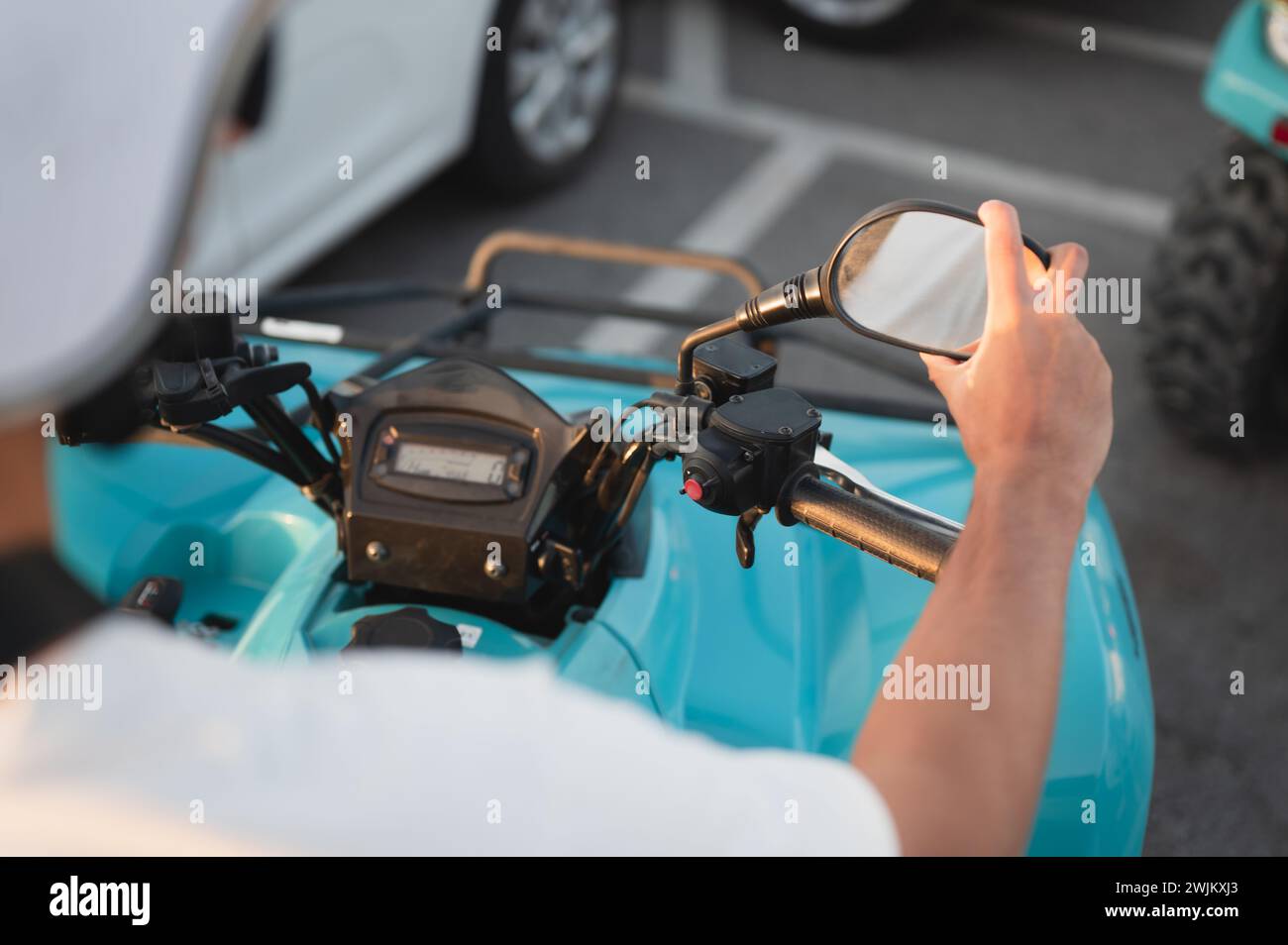 Persona che regola lo specchio sul quad a quattro ruote nel parcheggio Foto Stock