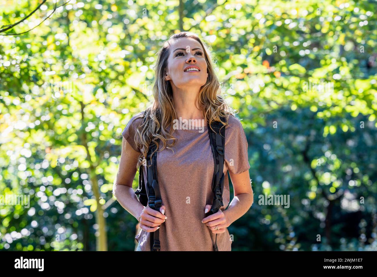 Bella donna che indossa lo zaino mentre cammina nel bosco Foto Stock