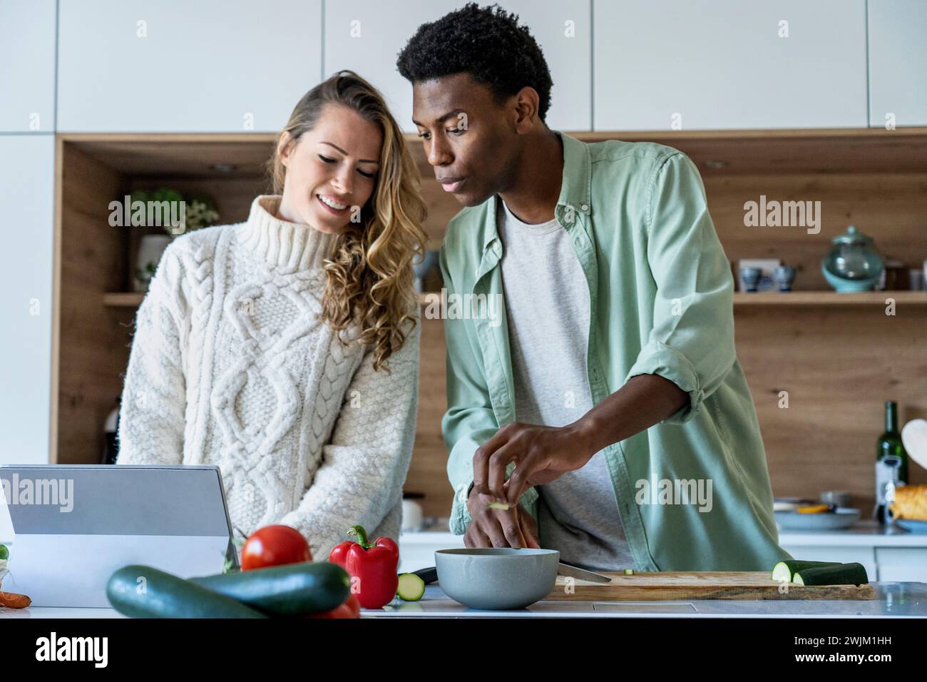 Coppia che guarda la ricetta di cottura su un tablet digitale mentre sta in piedi al bancone della cucina Foto Stock
