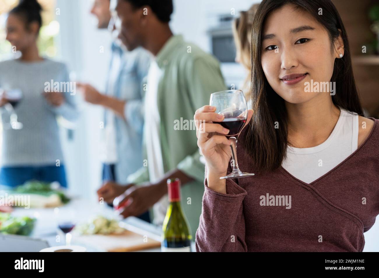 Giovane donna adulta che tiene in mano wineglass che guarda la macchina fotografica Foto Stock