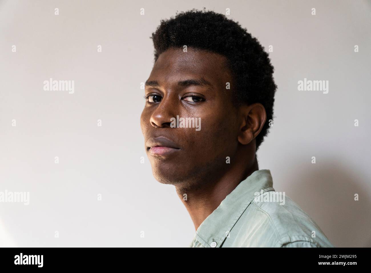 Ritratto con vista laterale di un giovane uomo adulto che guarda alla telecamera Foto Stock