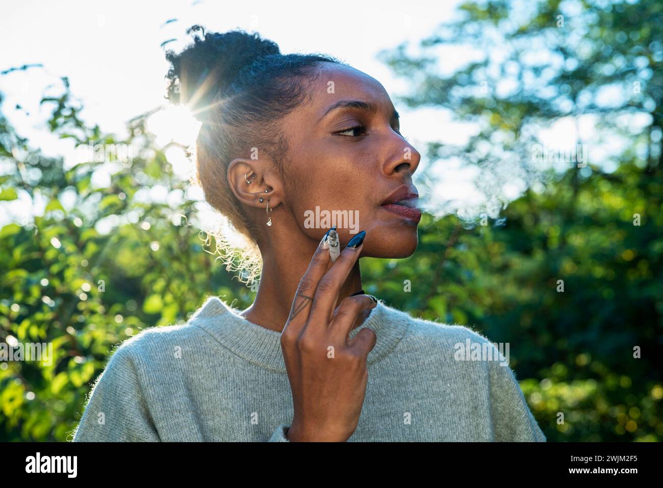 Donna adulta che fuma all'aperto durante il giorno Foto Stock