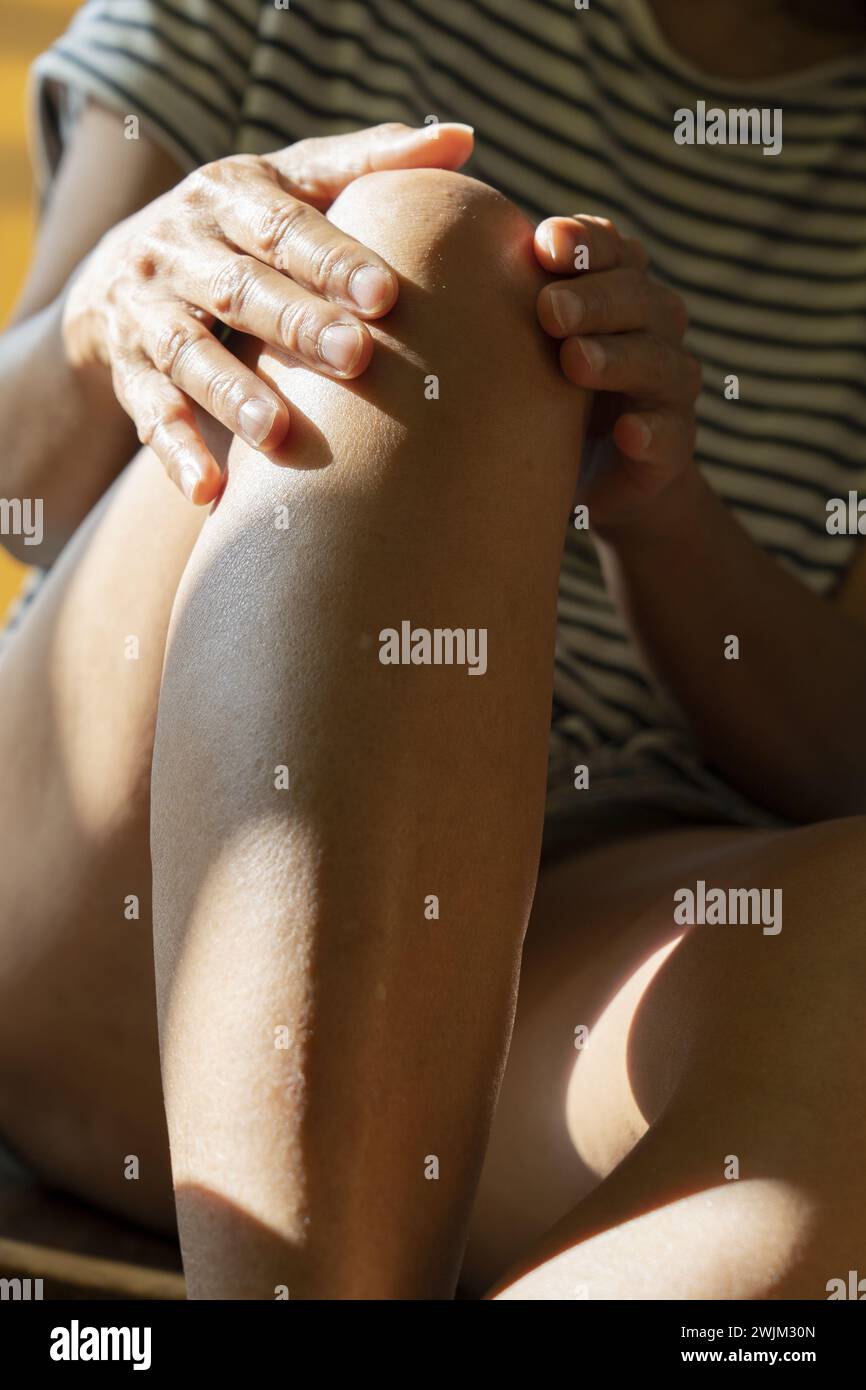 Le mani di una persona non identificata toccano le gambe Foto Stock
