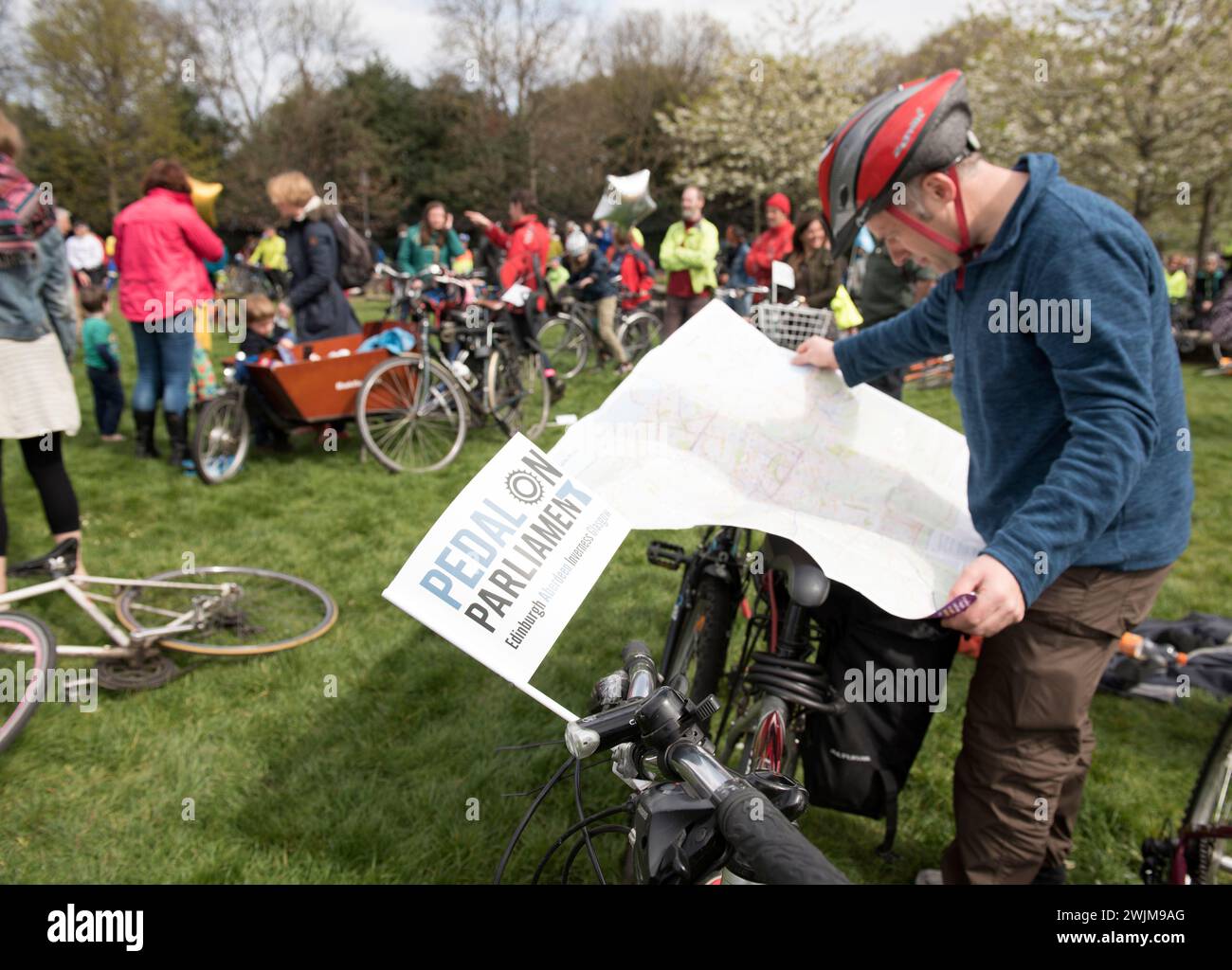 Un uomo con una ciclovia e una bicicletta studia una mappa di fronte a centinaia di ciclisti e persone con biciclette fuori dal Parlamento che hanno pedalato attraverso la t Foto Stock
