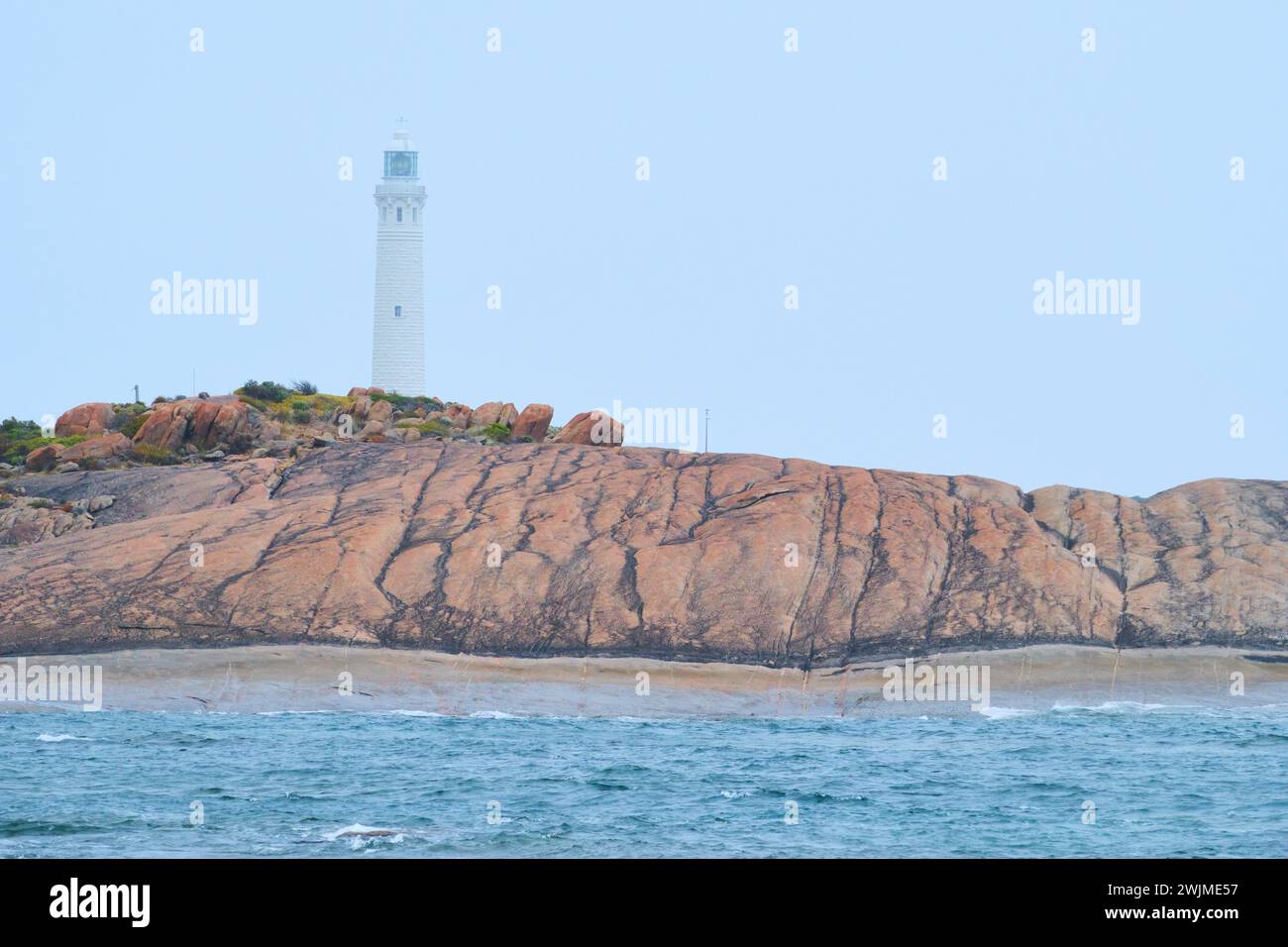 Faro di Cape Leeuwin in una mattinata nebbiosa con rocce di granito e oceano in primo piano, Cape Leeuwin, Australia sud-occidentale. Foto Stock