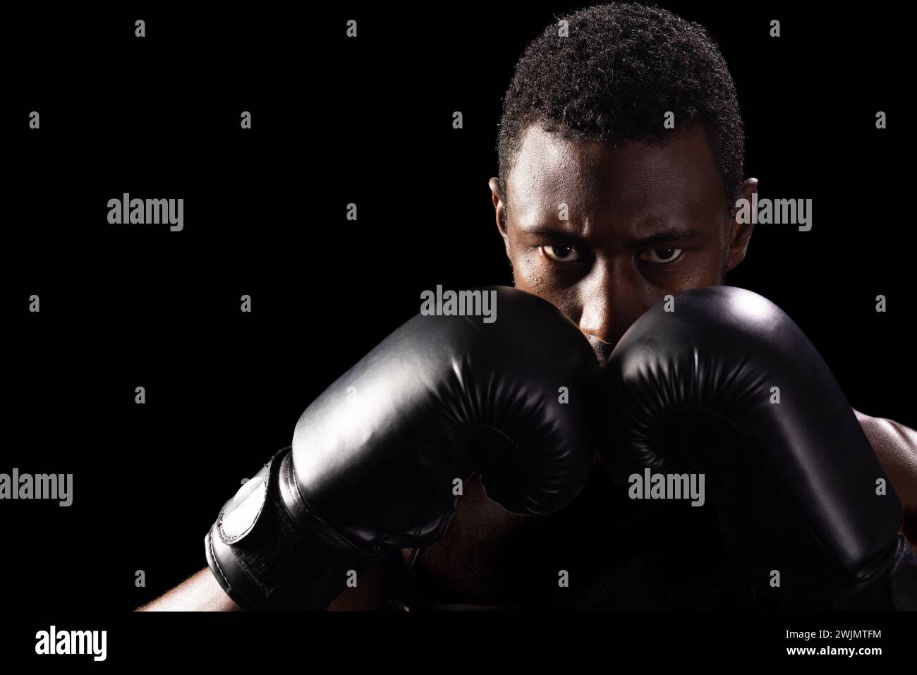 L'uomo afroamericano nei guanti da boxe si concentra intensamente Foto Stock