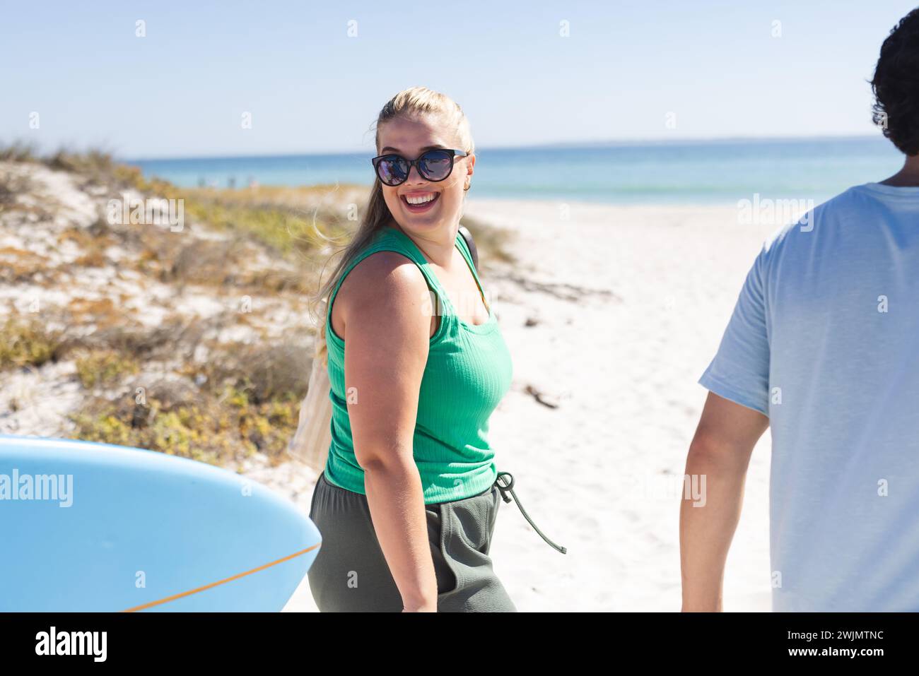 Amici diversi, tra cui una giovane donna caucasica e un uomo birazziale, si godranno una giornata di sole sulla spiaggia Foto Stock