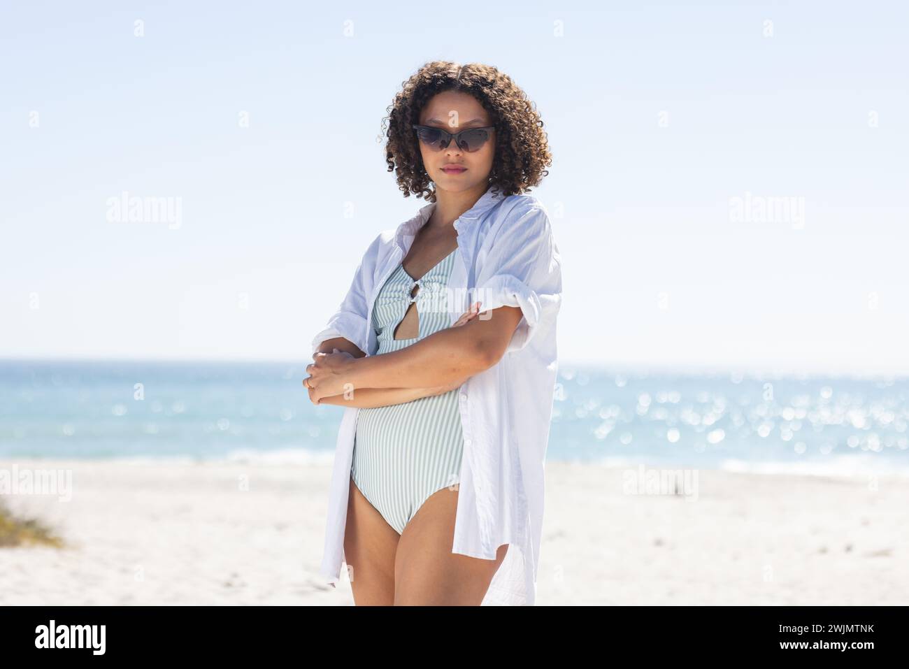 La giovane donna birazziale sta in piedi con fiducia sulla spiaggia Foto Stock