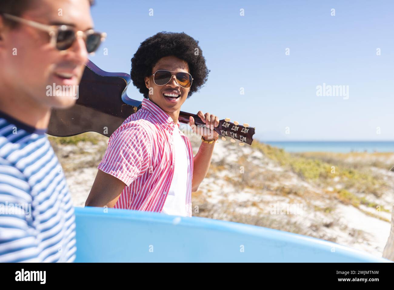 Il giovane uomo caucasico e afroamericano si godono una giornata di sole sulla spiaggia Foto Stock