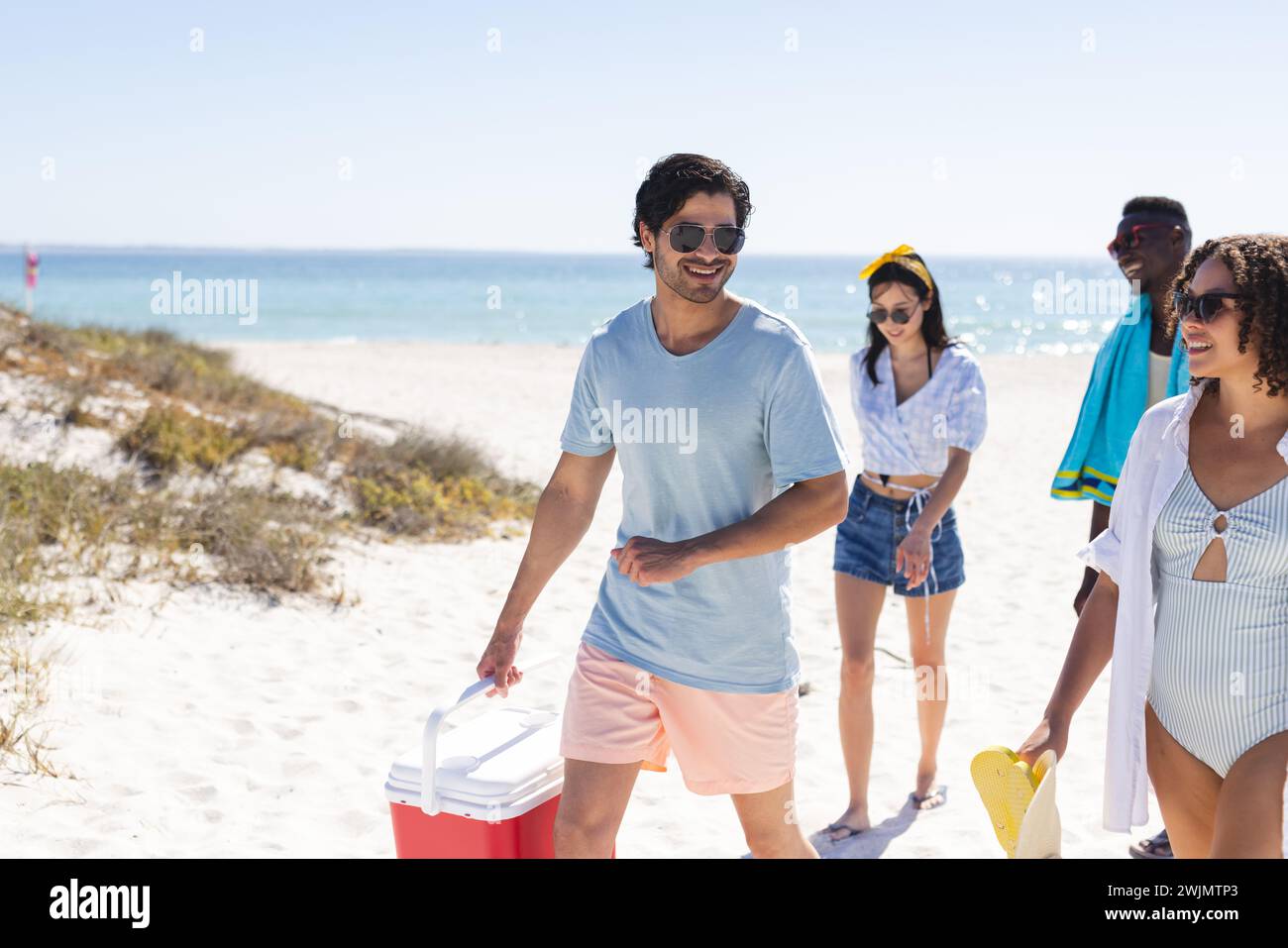 Un gruppo eterogeneo di amici gode di una giornata di sole in spiaggia Foto Stock