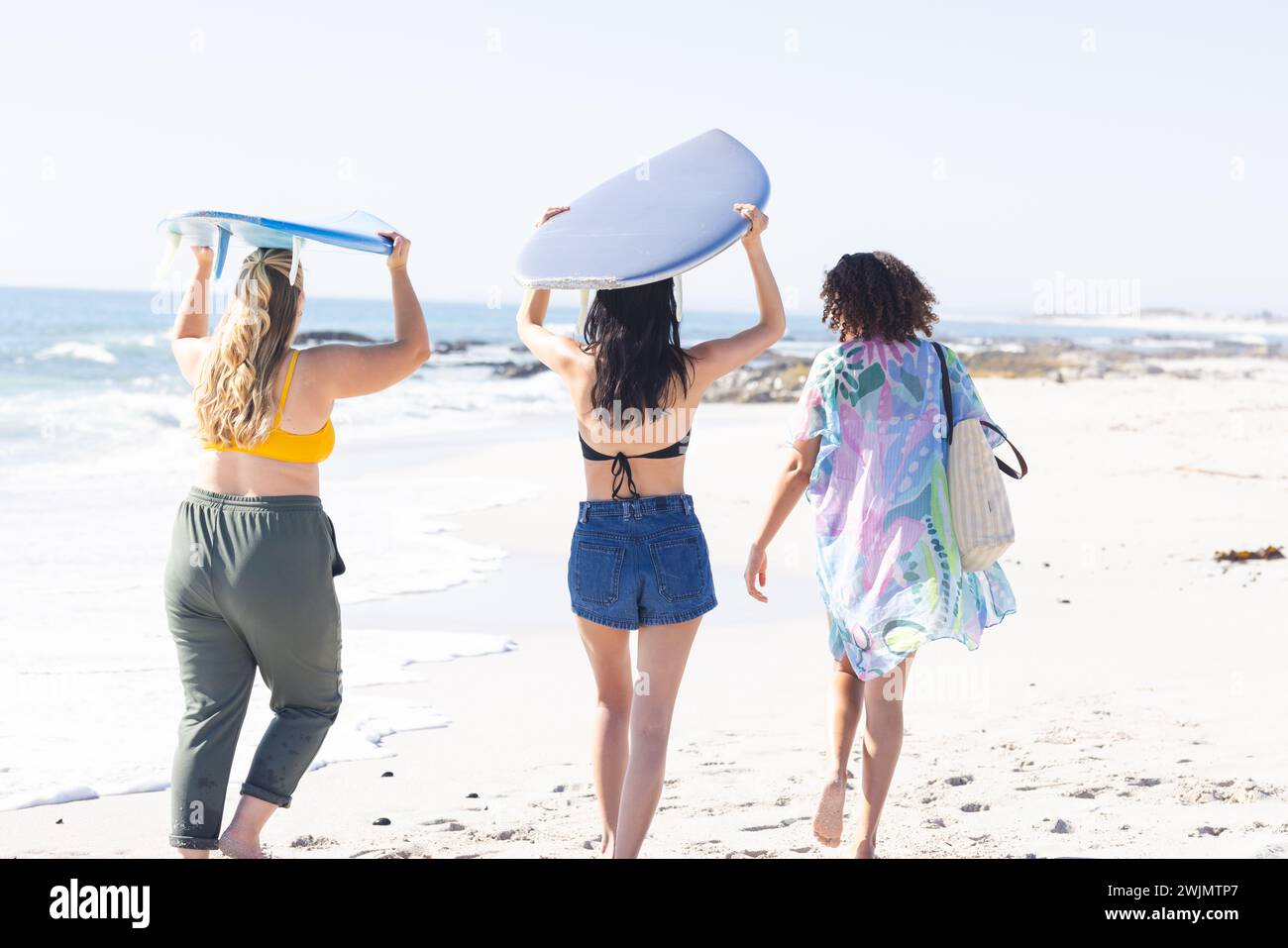 Giovani donne caucasiche e due giovani donne birazziali si divertono in spiaggia Foto Stock