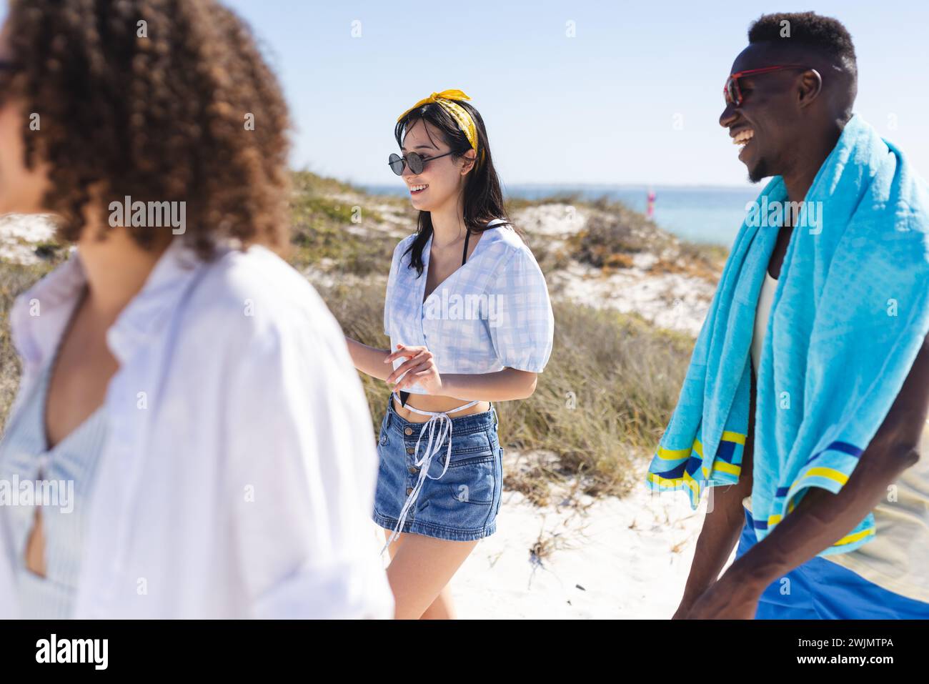 Le giovani donne birazziali e l'uomo afroamericano si godono una giornata di sole sulla spiaggia Foto Stock