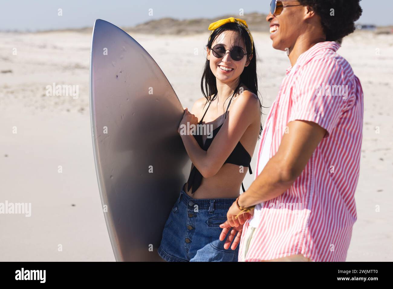 Giovane donna birazziale e uomo afroamericano si godono una giornata di sole sulla spiaggia Foto Stock