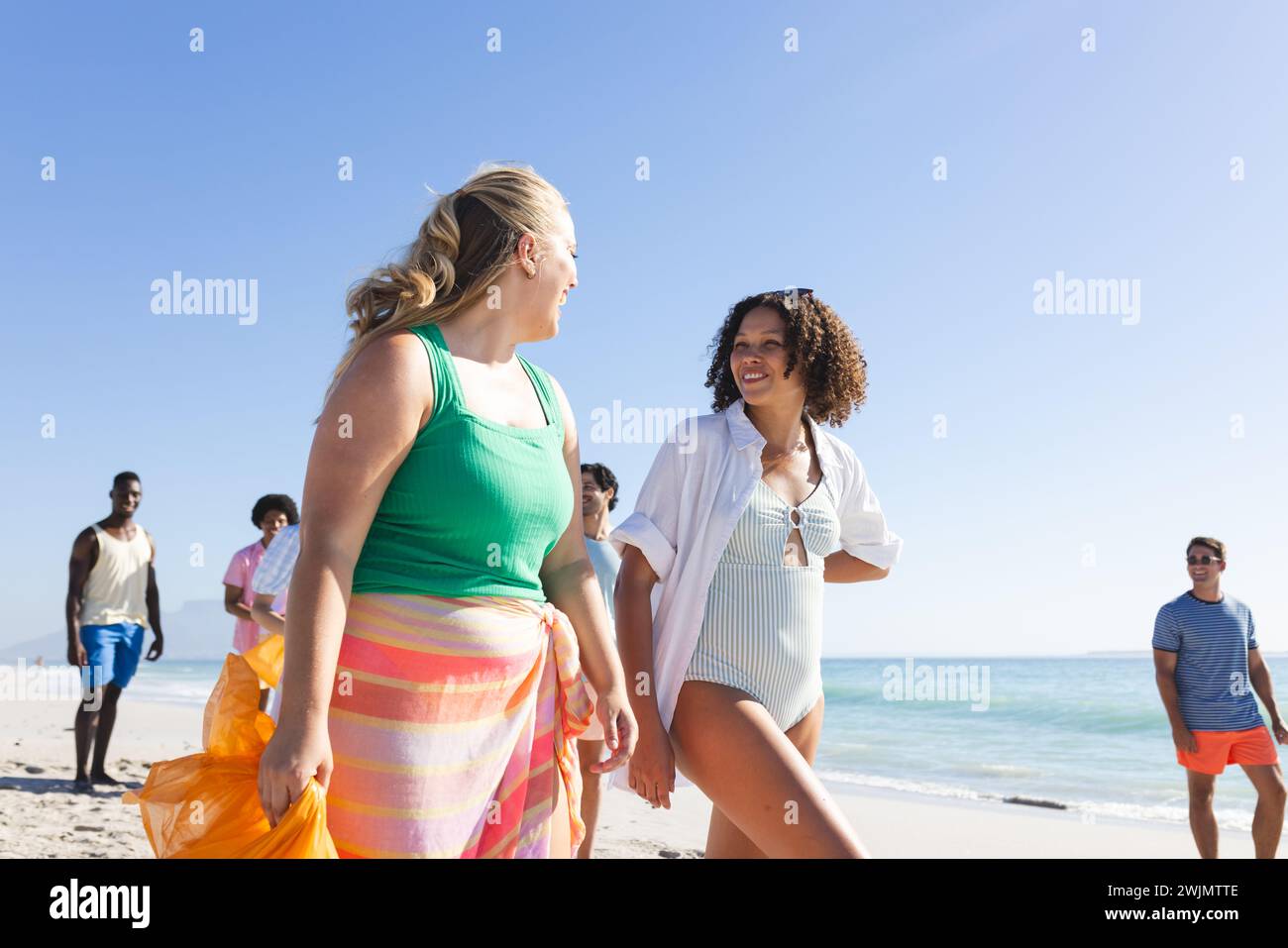Amici diversi si godono una giornata di sole sulla spiaggia raccogliendo spazzatura Foto Stock
