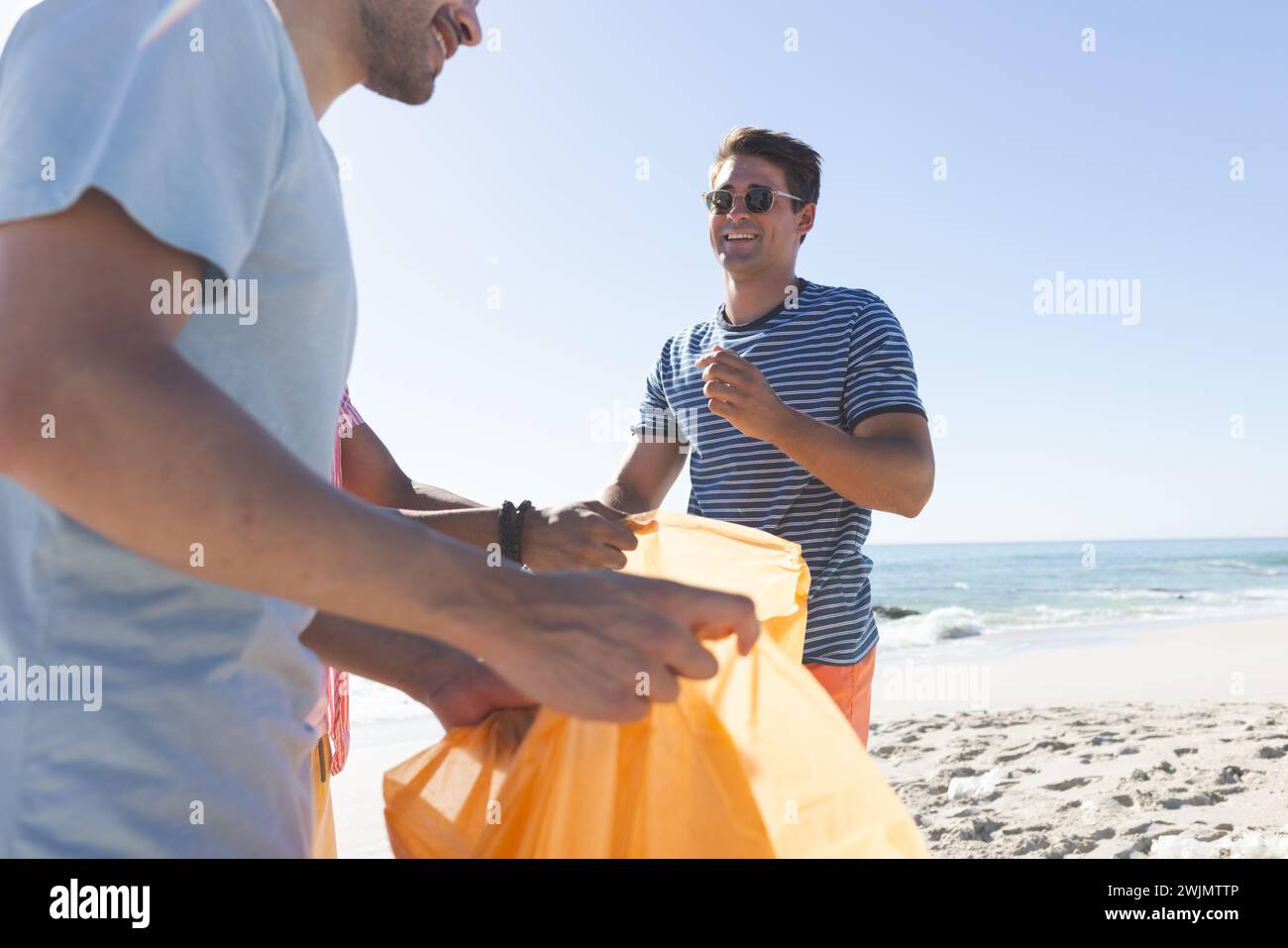 Due amici trascorrono una giornata di sole sulla spiaggia raccogliendo rifiuti Foto Stock