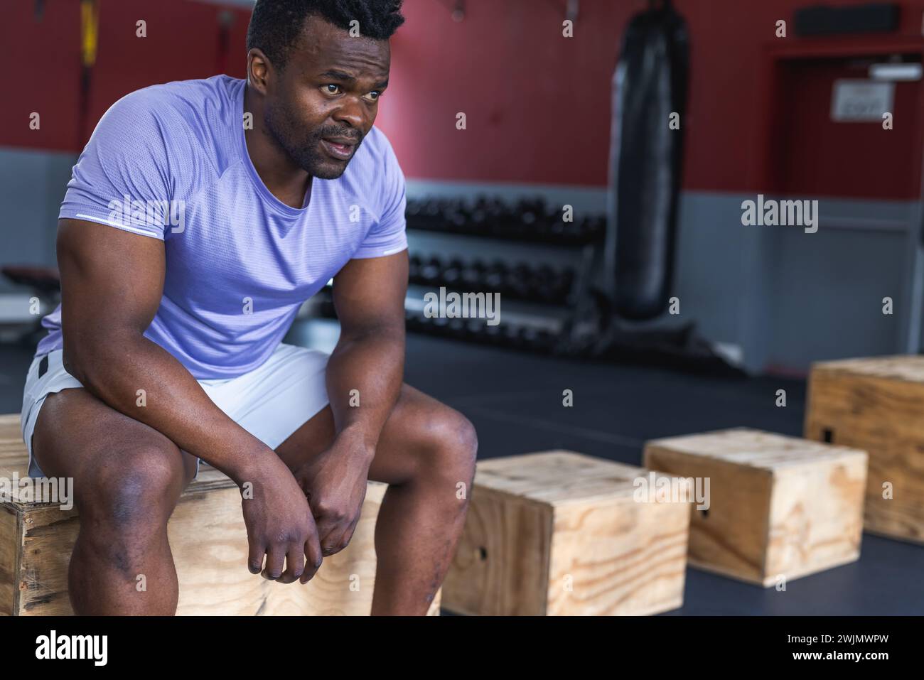 Un uomo afroamericano in forma riposa durante un allenamento in palestra Foto Stock