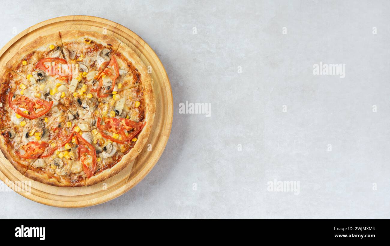 Pizza italiana fatta in casa con funghi di mozzarella, mais e pomodoro su un piatto rotondo di legno su sfondo bianco di cemento. Banner, intestazione con Foto Stock