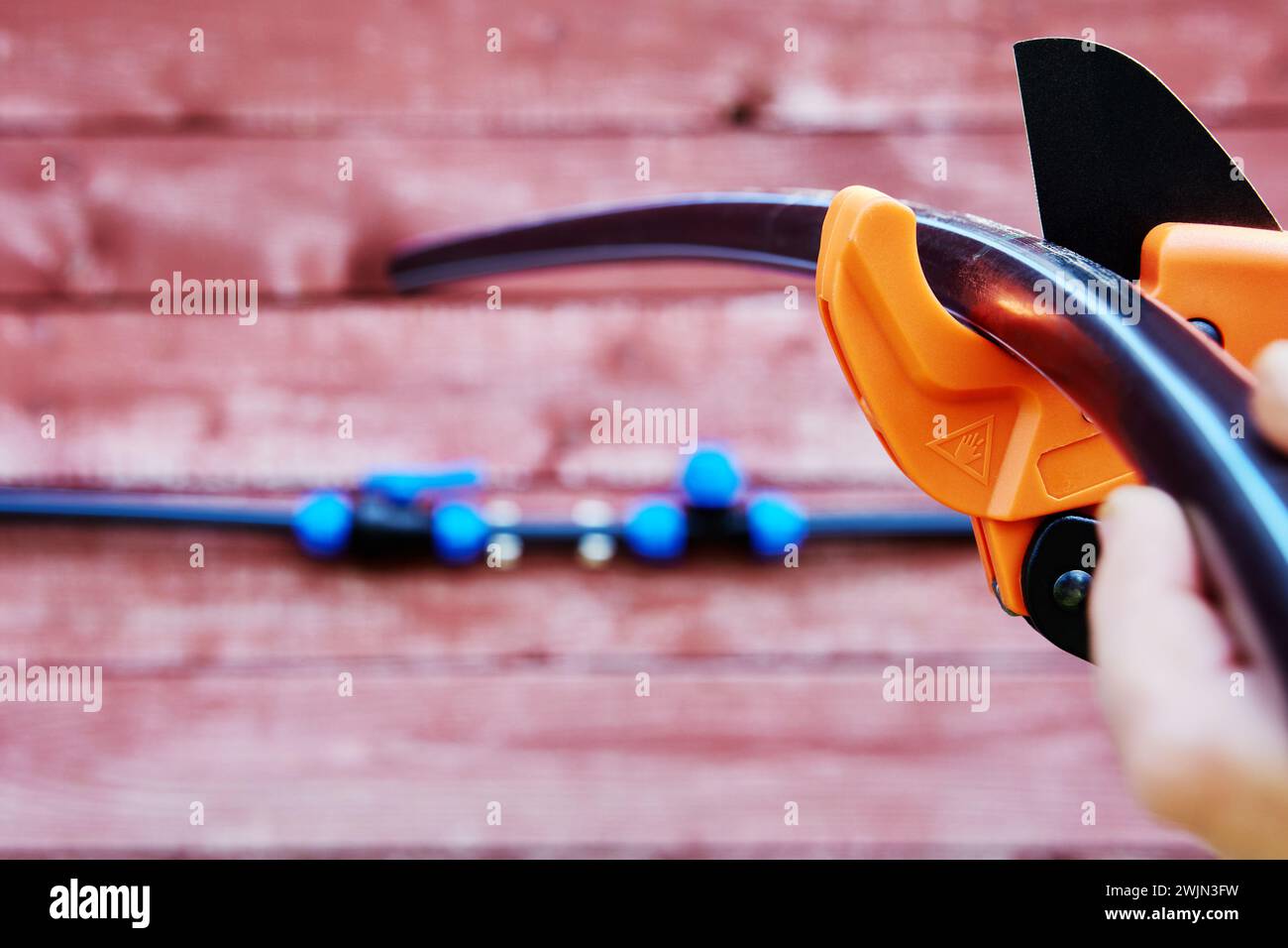 Installazione di una conduttura esterna per l'irrigazione e l'acqua potabile, il lavoratore taglia tubi in HDPE con un tagliatubi. Foto Stock