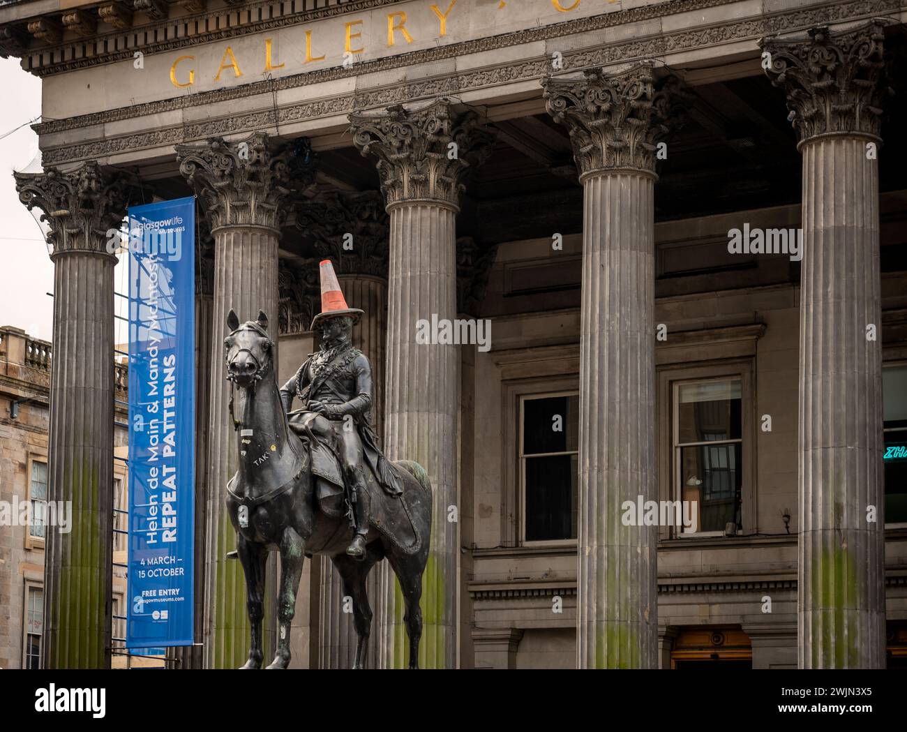L'esterno a pilastri della Gallery of Modern Art GOMA a Glasgow in Scozia mostra la statua del duca di wellington con un cono stradale sul suo He Foto Stock