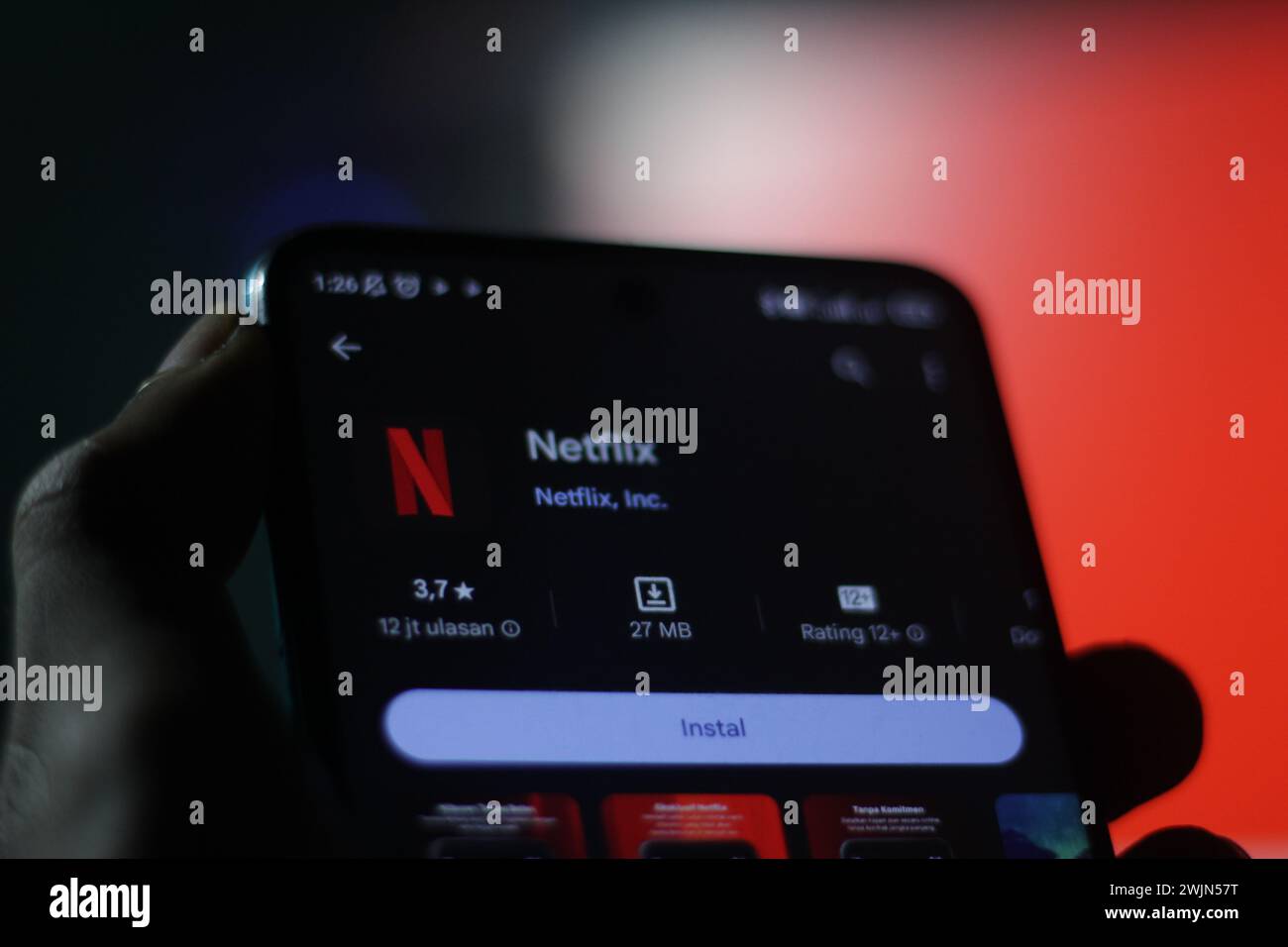 Una mano di un uomo tiene un cellulare con il logo Netflix sullo schermo del cellulare. schermata di messa a fuoco selettiva dell'app appstore. Editoriale illustrativo Foto Stock