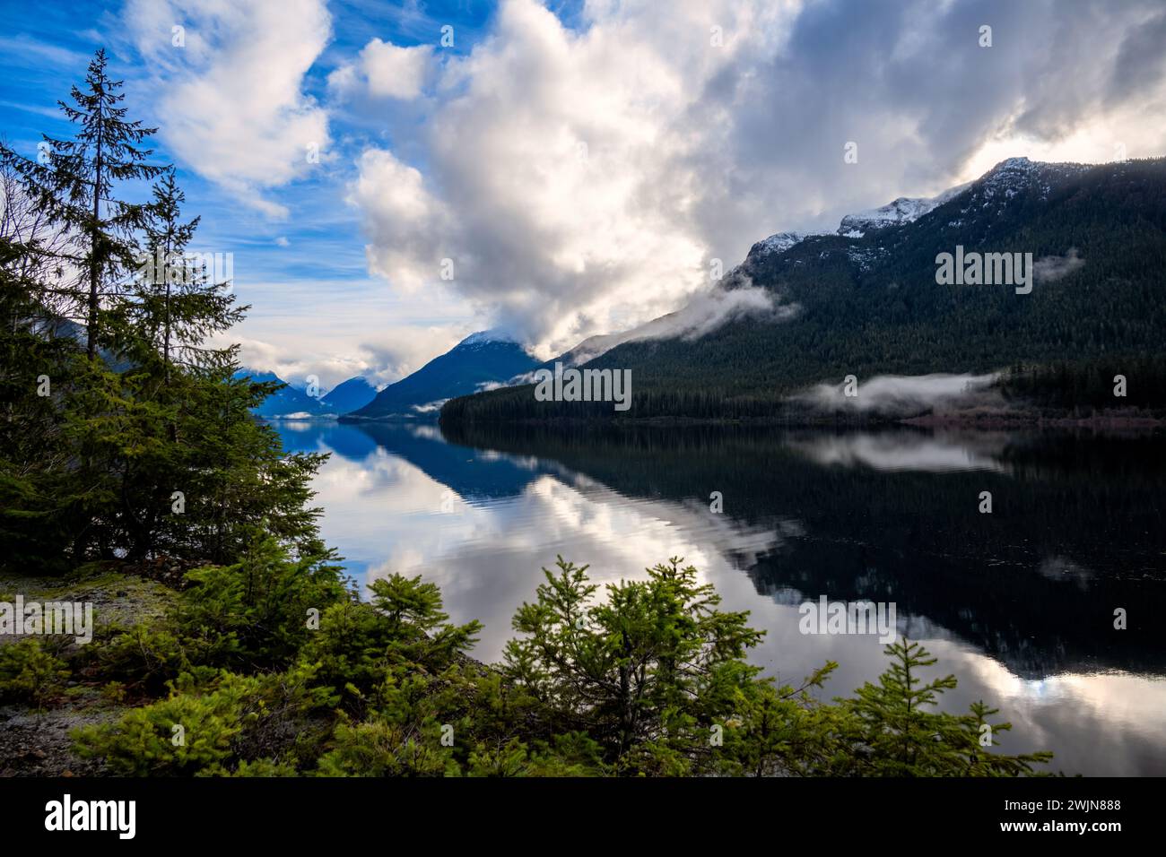 Tranquillo lago di montagna con nuvole e pini Foto Stock