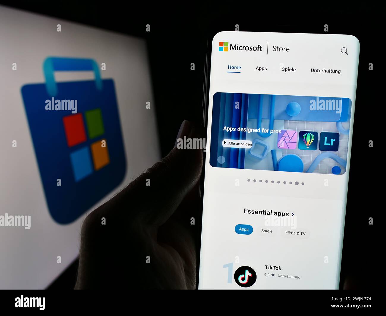 Persona che detiene lo smartphone con il sito Web della piattaforma di distribuzione digitale Microsoft Store davanti al logo. Messa a fuoco al centro del display del telefono. Foto Stock