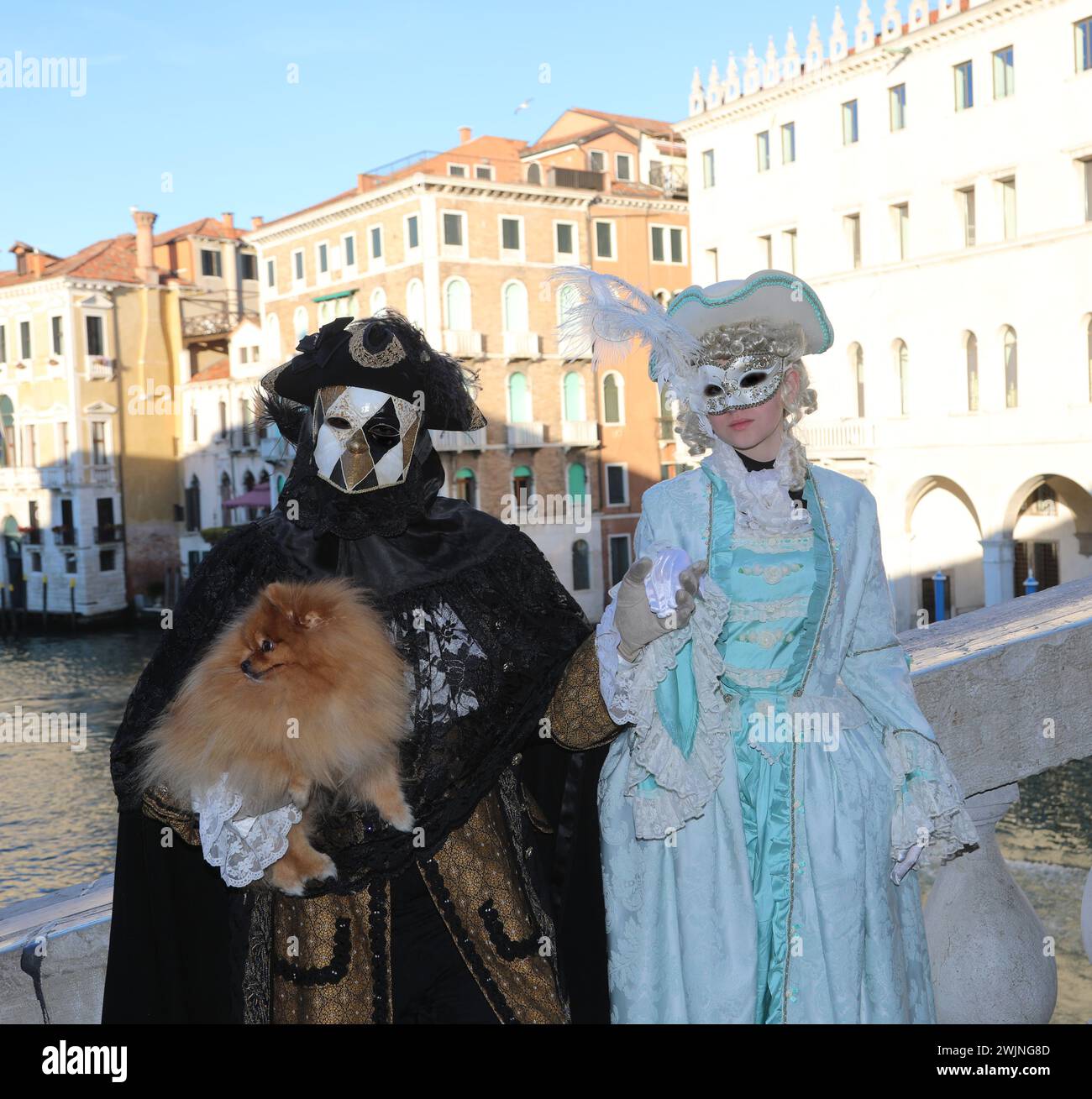 Venezia, VE, Italia - 13 febbraio 2024: Due persone mascherate e un cane sul ponte di rialto durante il carnevale Foto Stock