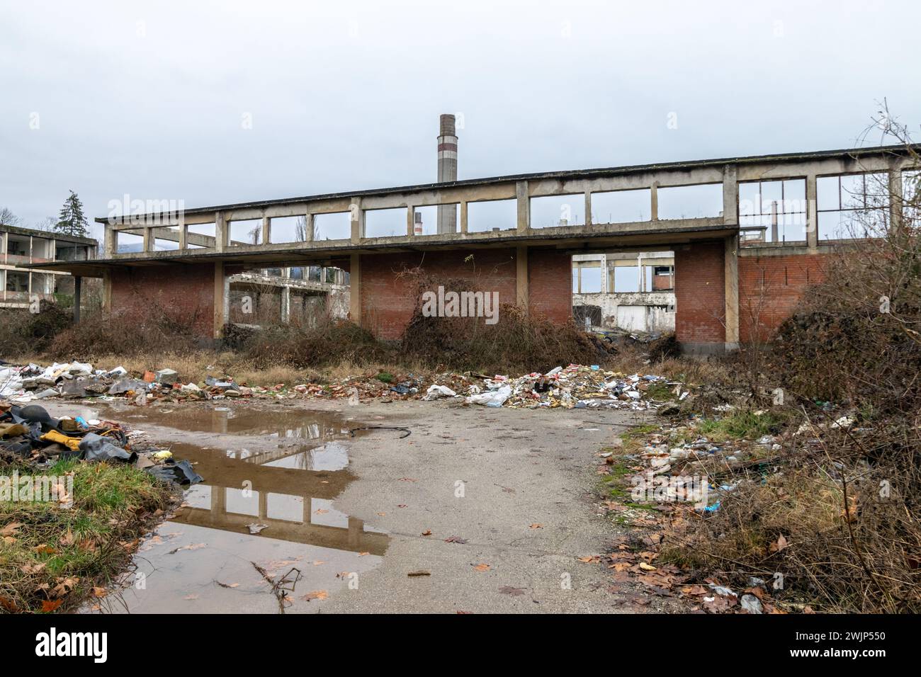 Resti di una vecchia fabbrica chimica saccheggiata, crollata e fatiscente acqua di pozzanghera Foto Stock