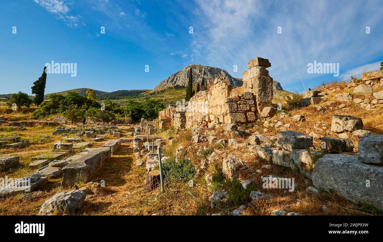 Rovine di antiche strutture sotto un cielo azzurro circondate dalla vegetazione mediterranea, sito archeologico, Archea Korinthos, Corinto, Peloponneso Foto Stock