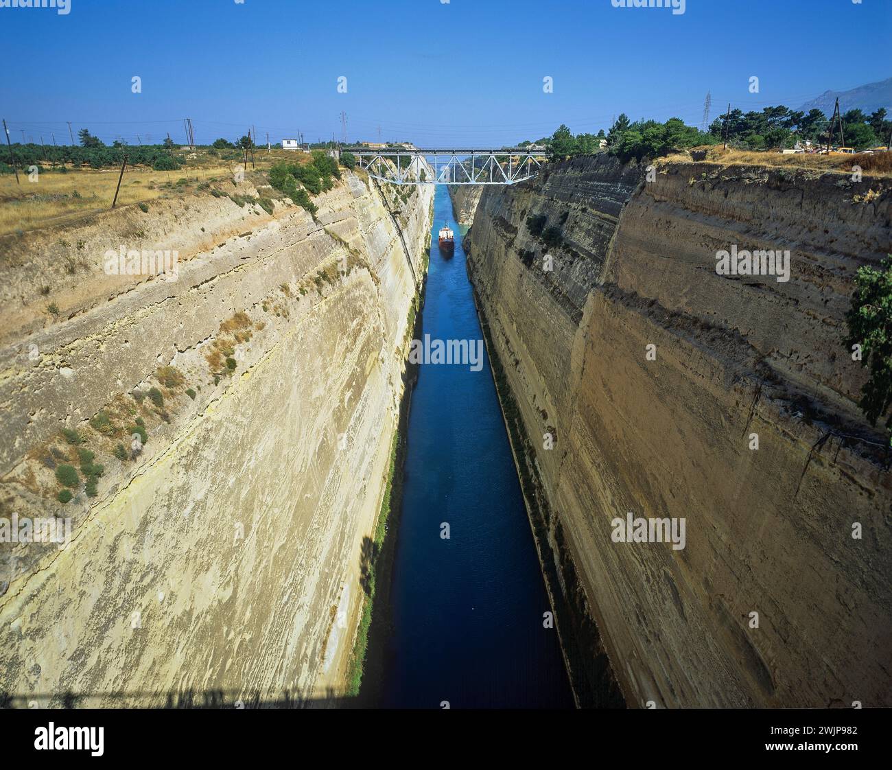 Una nave da carico viaggia attraverso un corso d'acqua simile a un canale con pareti ripide e asciutte, il canale di Corinto, Corinto, Peloponneso, Grecia Foto Stock