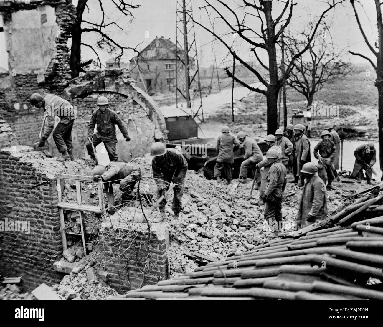 German Bricks Aid Allied Advance Inside Reich -- gli ingegneri del Nono Esercito degli Stati Uniti demoliscono un muro a Ubach, in Germania, e caricano i detriti sui camion, da utilizzare per riparare le strade per aiutare l'avanzata alleata all'interno del Reich, Stati Uniti 8 gennaio 1945. (Foto dell'Office of War Information Picture statunitense). Foto Stock