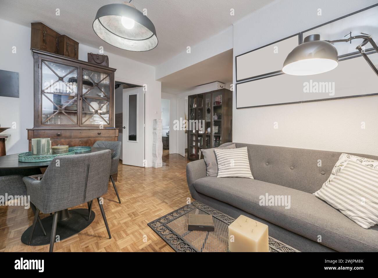 Piccolo soggiorno in una casa con mobili e accessori che combinano stile vintage e contemporaneo, pavimenti in parquet, divano in tessuto grigio e matchin Foto Stock