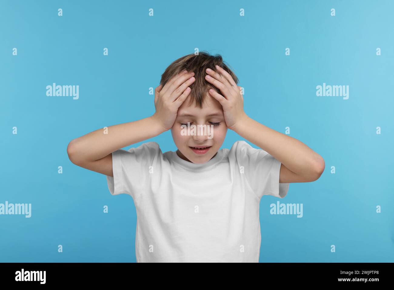 Bambino che soffre di mal di testa su sfondo azzurro Foto Stock